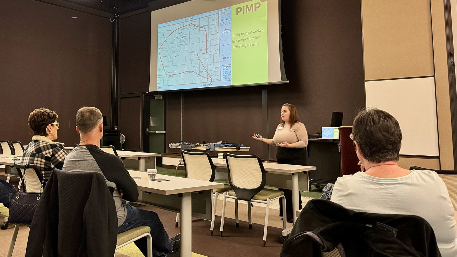 Terri Markham explains the concept of "pimping" in human trafficking. The slide on the screen shows a route used by sex workers, victims of human trafficking, who moved throughout Wyoming as part of a pimp-controlled trafficking business.