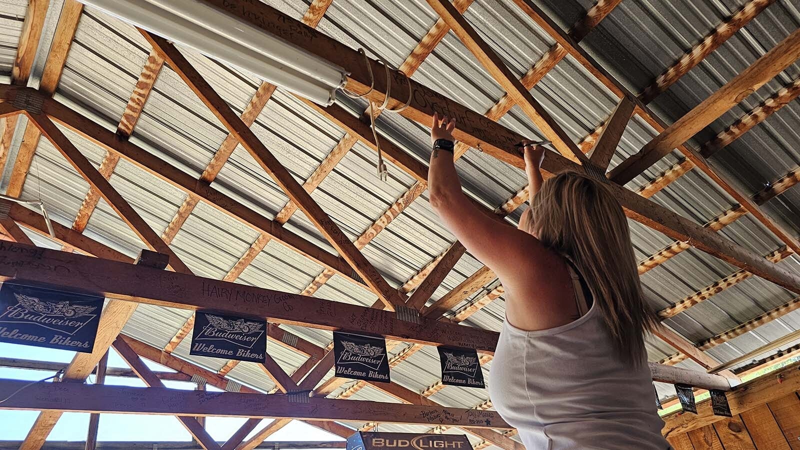 Ashley Overturf, of Dallas, adds her name and the date to a rafter at Captain Ron’s Rodeo Bar & Lounge during Hulett's Ham and Jam.
