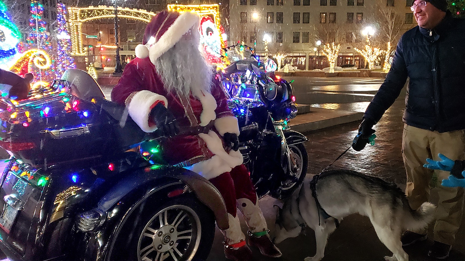 Santa, aka Rick Ramos, rides his lighted Harley around Cheyenne. Here he chats with a family walking their dog at Depot Plaza.
