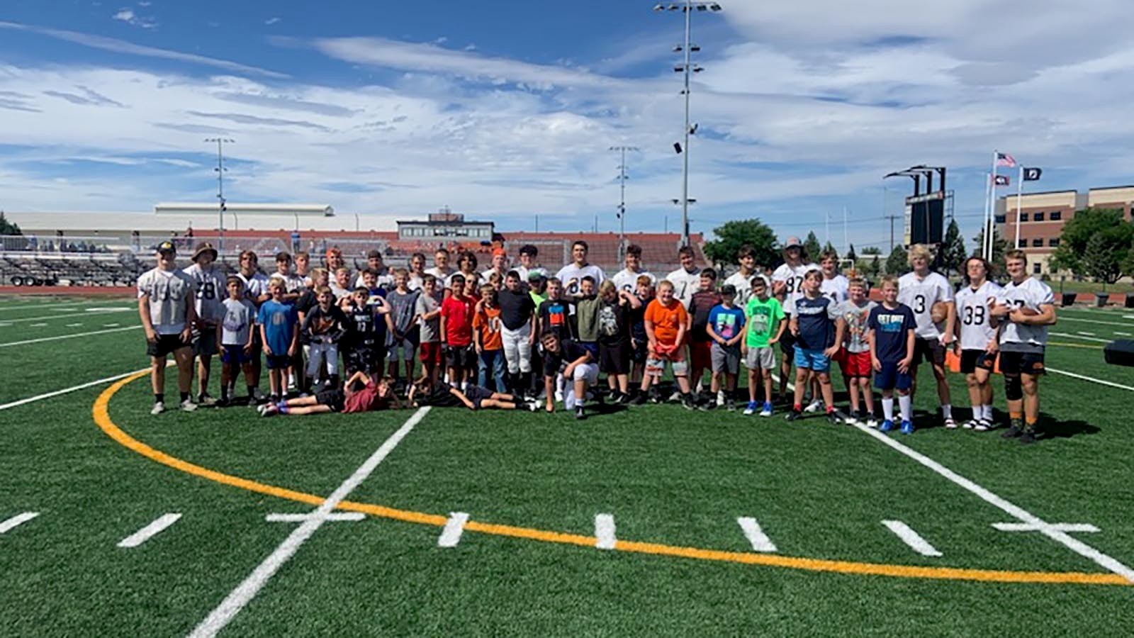 Community service is part of the learning on the Natrona County High School football team. Here members pose with youngsters participating in the youth football camp.