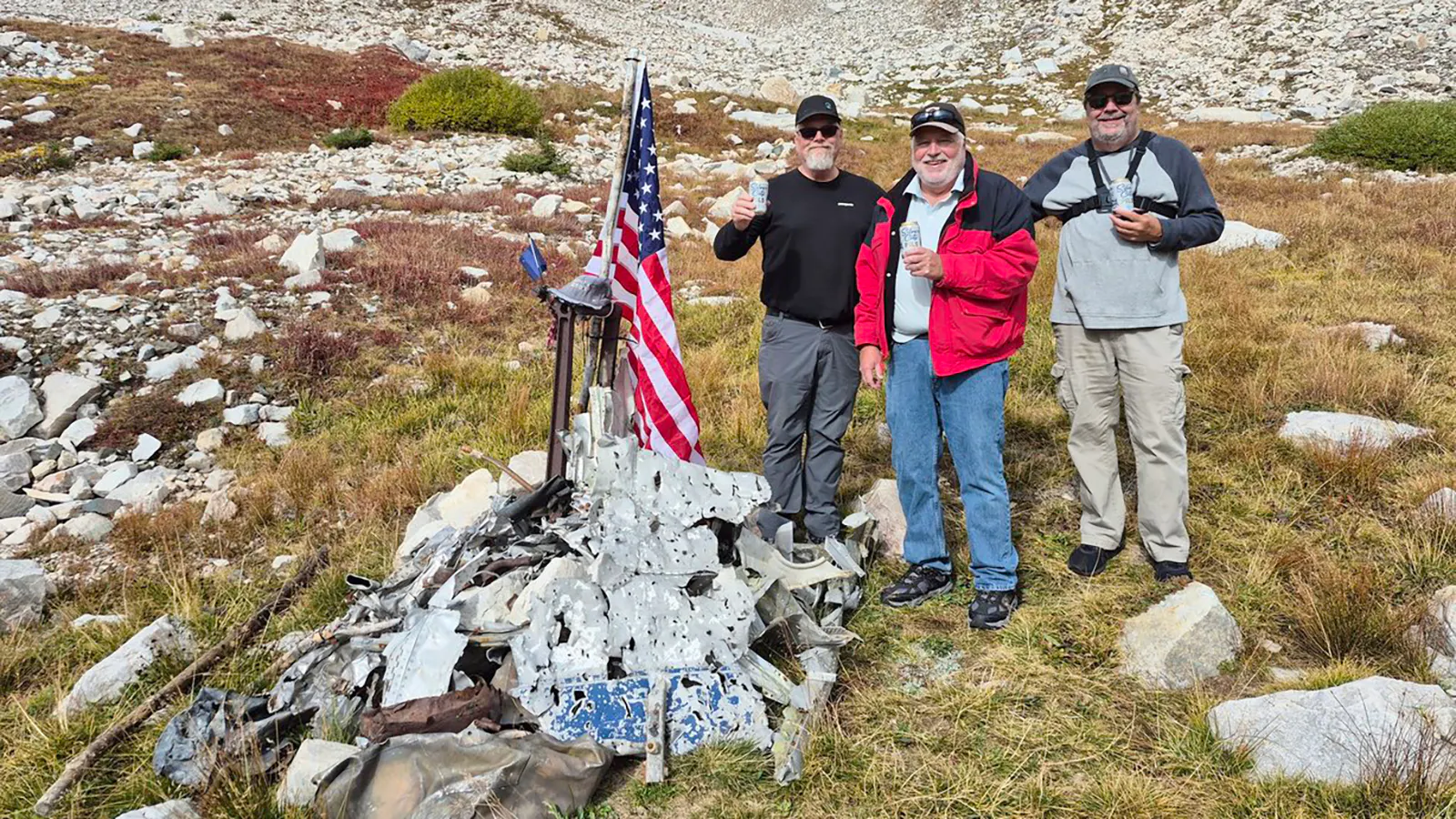 The Tanis brothers — Daniel, Rick and Roger — pose at the Medicine Bow Peak crash site where they placed their dad’s ashes, a special hat, and flag.