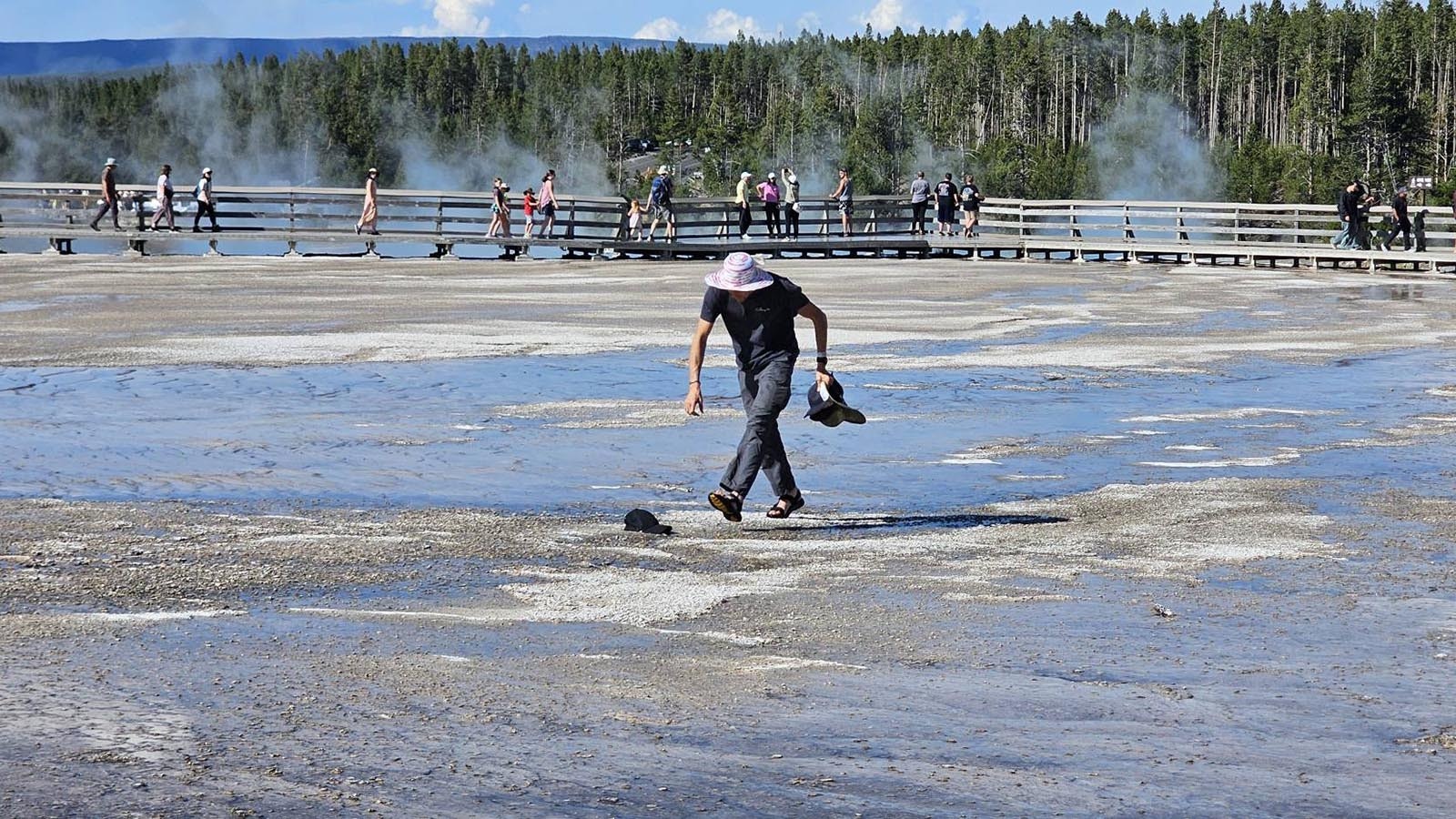Other Yellowstone visitors were horrified Monday as they watched a man in flip-flops walking off the board walk onto the bacterial mats around Grand Prismatic Spring. He was picking up hats that had blown off people’s heads — and breaking the law.
