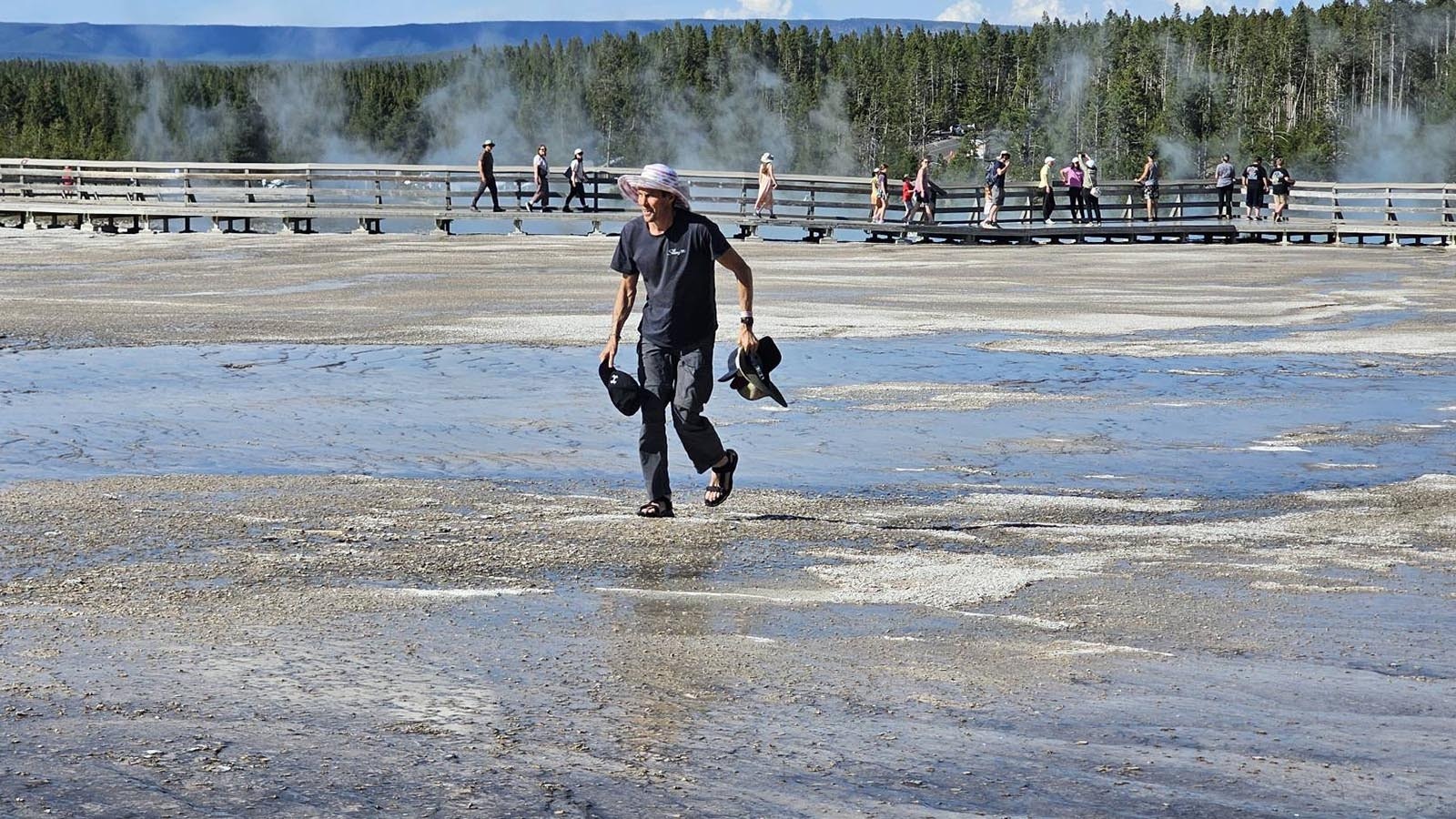 Other Yellowstone visitors were horrified Monday as they watched a man in flip-flops walking off the board walk onto the bacterial mats around Grand Prismatic Spring. He was picking up hats that had blown off people’s heads — and breaking the law.