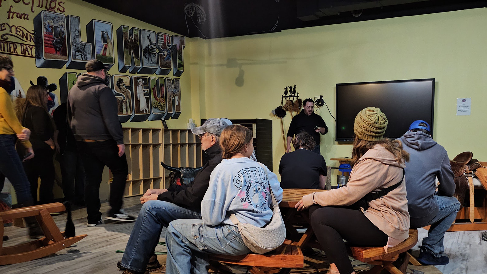 A group of people listen as Marty Perez talks about the spirits beloved to haunt the Hole in the Wall playroom at the CFD Old West Museum.