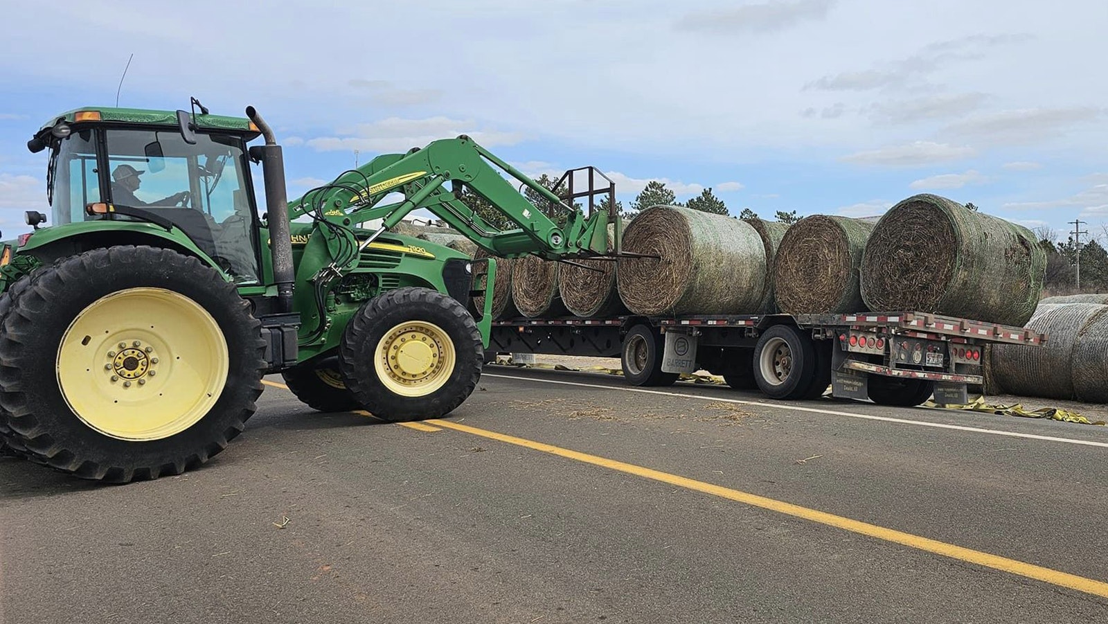 A large flatbed trailer loaded with Wyoming hay is unloaded in Texas.