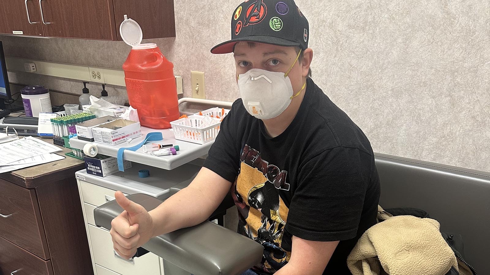 Ayden Skillman about to give blood gives his mom a thumbs up.