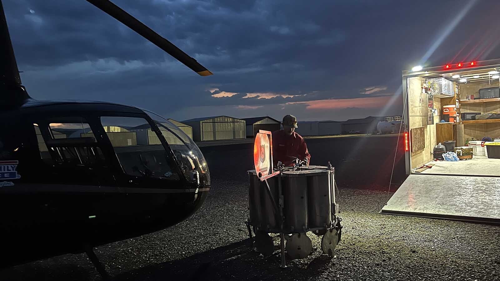 Kris Holmes, the statewide spawning coordinator for the Wyoming Game and Fish Department, prepares a cluster of cylinder-shaped fish tanks just as dawn breaks Tuesday at the Dubois Municipal Airport.