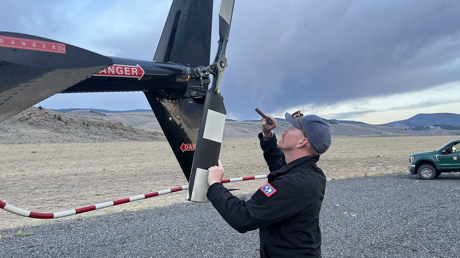 Pilot Emmett Webb of Rugged Mountain Aviation commercial helicopter services performs a pre-flight inspection on a Robinson R66 helicopter early Tuesday at the Dubois Municipal Airport.
