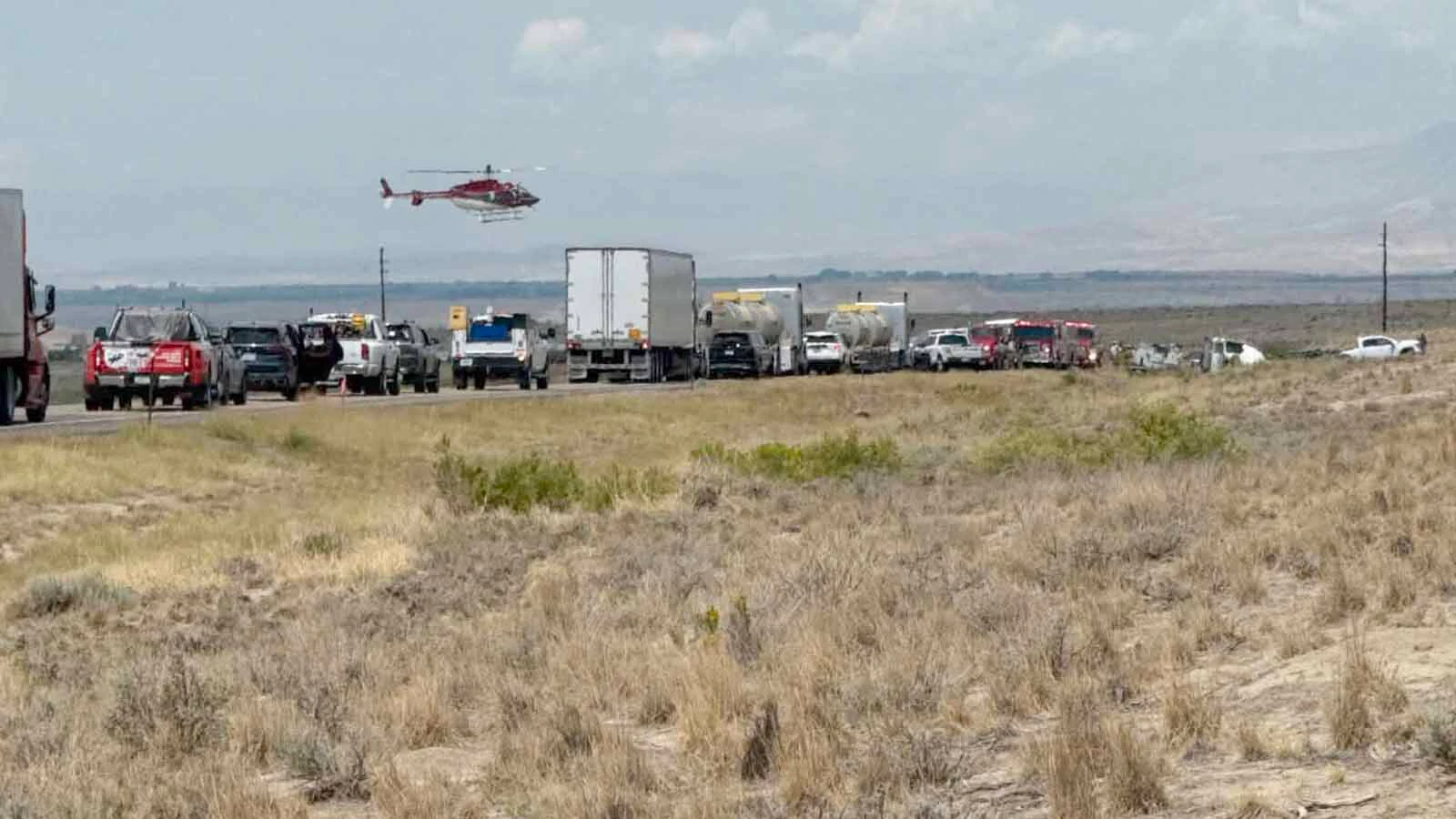 A helicopter flies over the scene of Wednesday's crash on U.S. 20/26 east of Shoshoni as emergency responders assist those involved.
