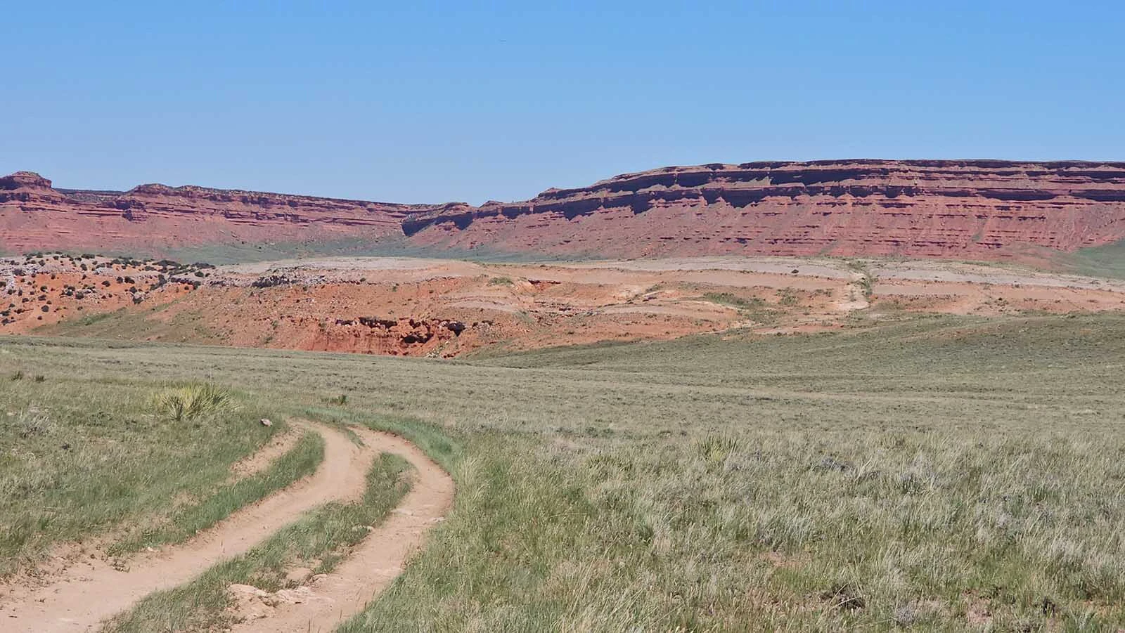 The Hole in the Wall is actually a notch in a towering red cliff that rises 400 feet above the grassland that is just big enough for one person to squeeze through.
