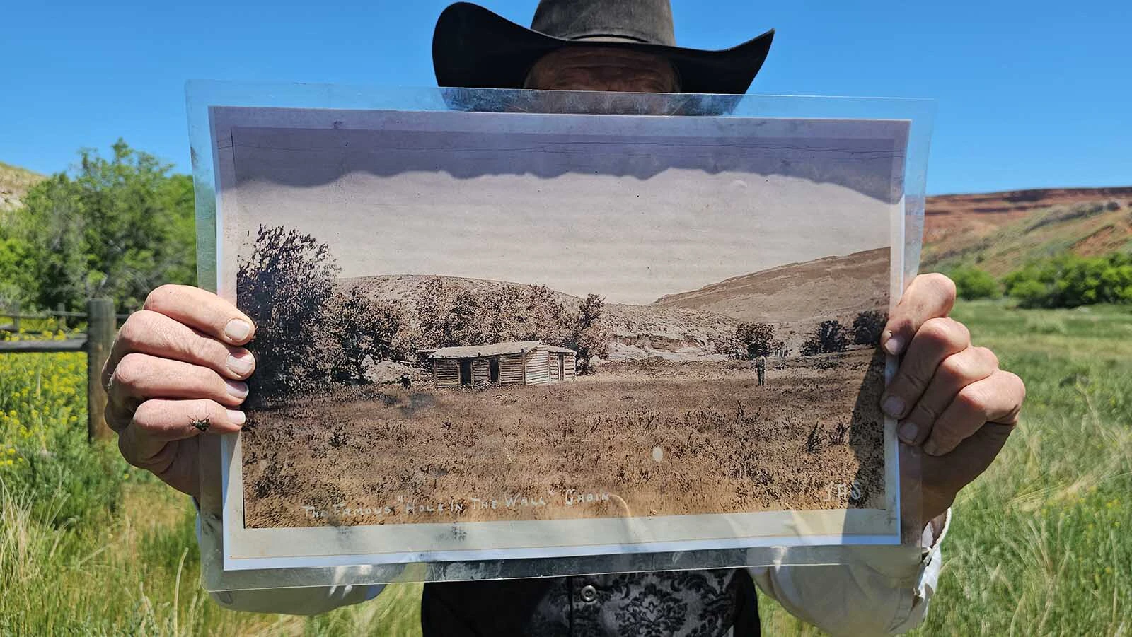 A then and now view. Clay Gibbons holds up a photo, then invites participants of his 2024 tour to take a look at the photo and then at the scenery, and see if they aren't standing right where the photographer who took that photo stood.