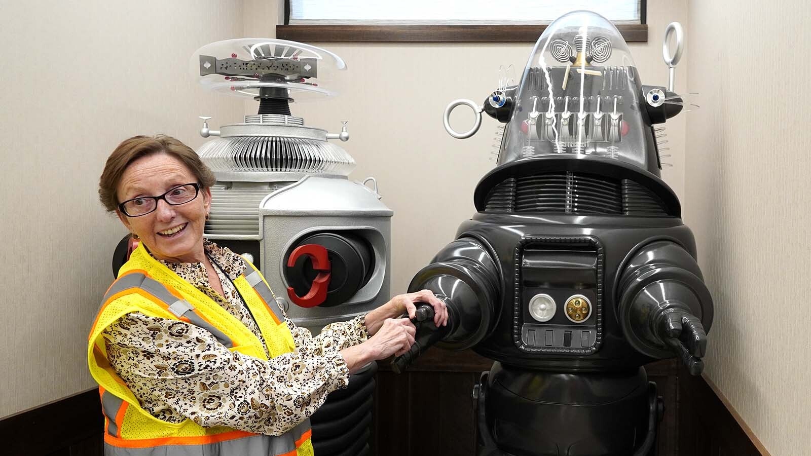 Patty Hoskinson with the walking talking robots. On the left, the robot from “Lost in Space,” and on the right, the robot from "The Forbidden Planet."