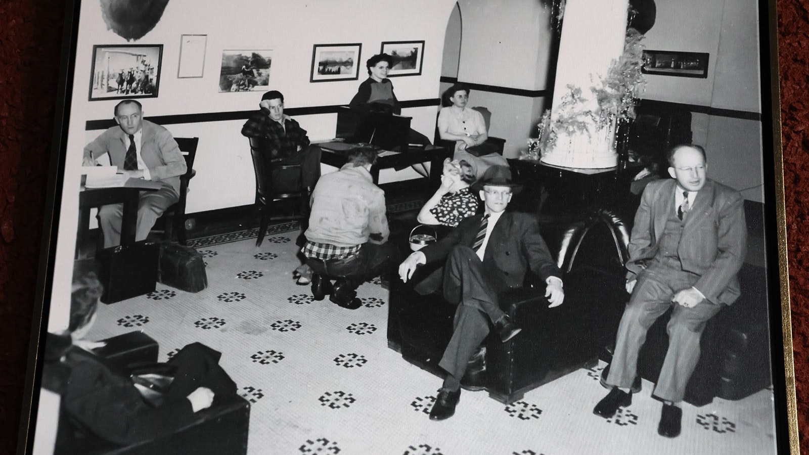 An old photo on the hotel wall shows patrons in the Hotel LaBonte lobby possibly around the holidays. The pillars are decorated.