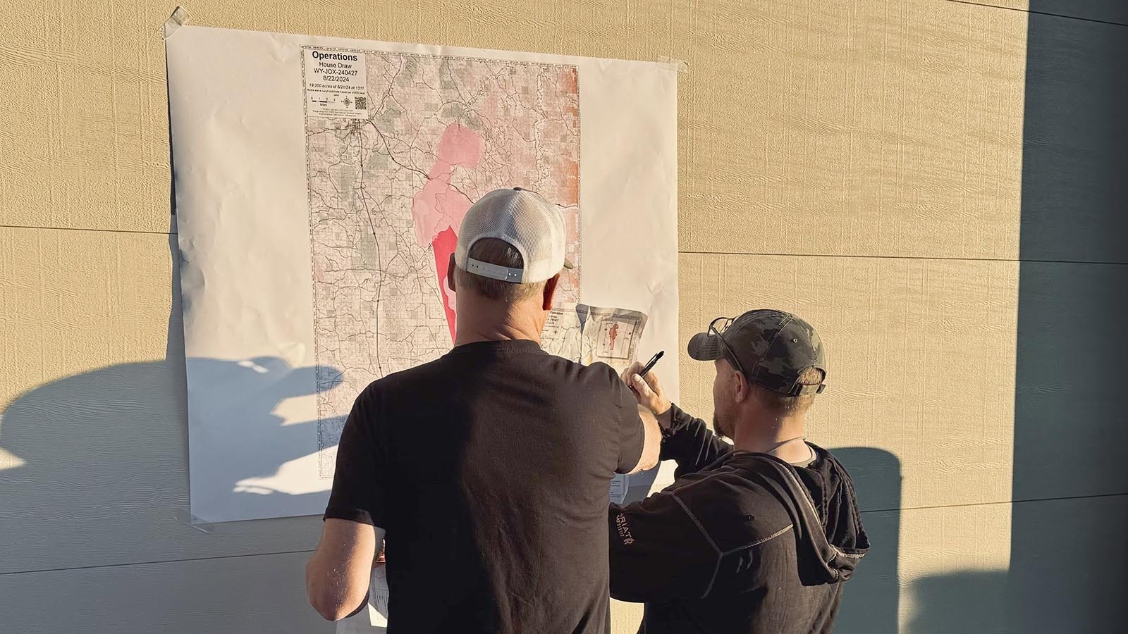 Firefighters look at a map of the 174,00-acre House Draw Fire posted on the garage door of the Buffalo Volunteer Fire Department.