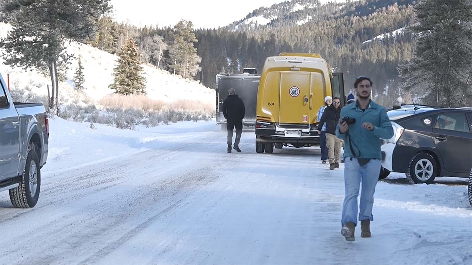 Tourists piling out of tour van parked in the middle of the road in Yellowstone National Park, which is against park rules. They also park in the flow of traffic.