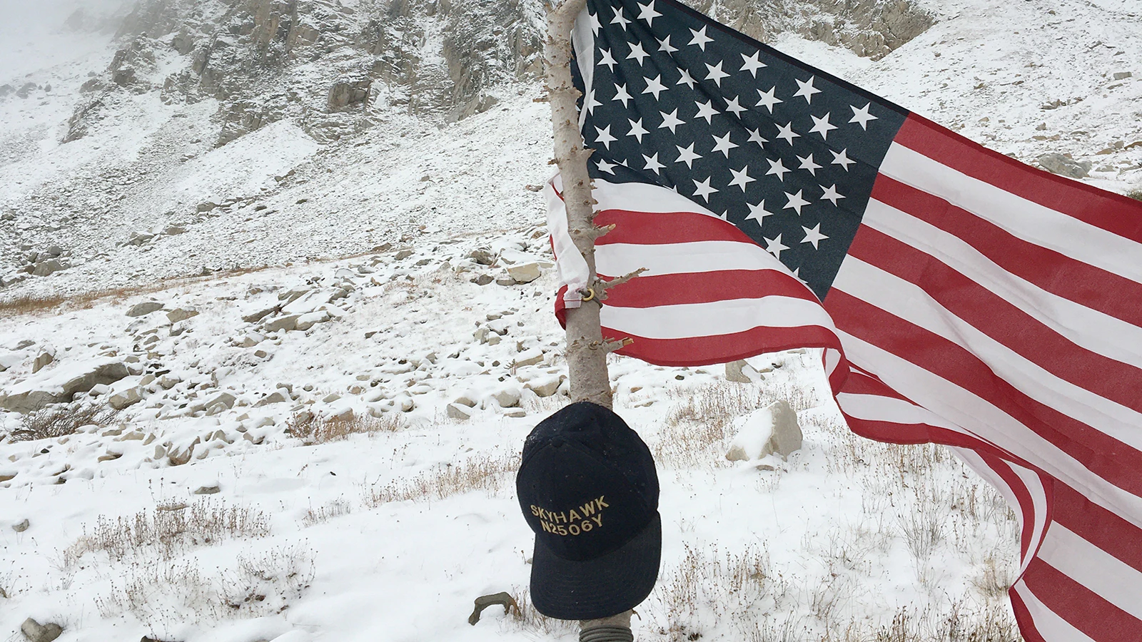 The initial flag honoring Flight 409 victims and a hat honoring Ralph Tanis was placed on the mountain in October 2019 as a storm moved in.