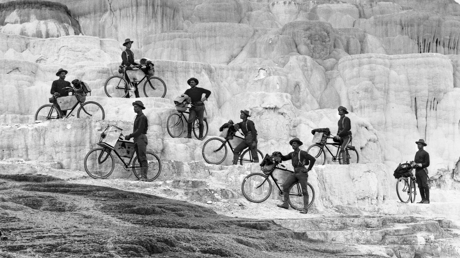 The 1896 Bicycle Corps riders pose on the Minerva Terrace, Yellowstone National Park. Before their historic 1,900-mile ride, eight of the men, led by Moss of Fort Missoula, rode to the park. John Findley, the mechanic, is front left, notice the big box on his handlebars. He did both the 1896 ride to Yellowstone and the 1897 ride to St. Louis.