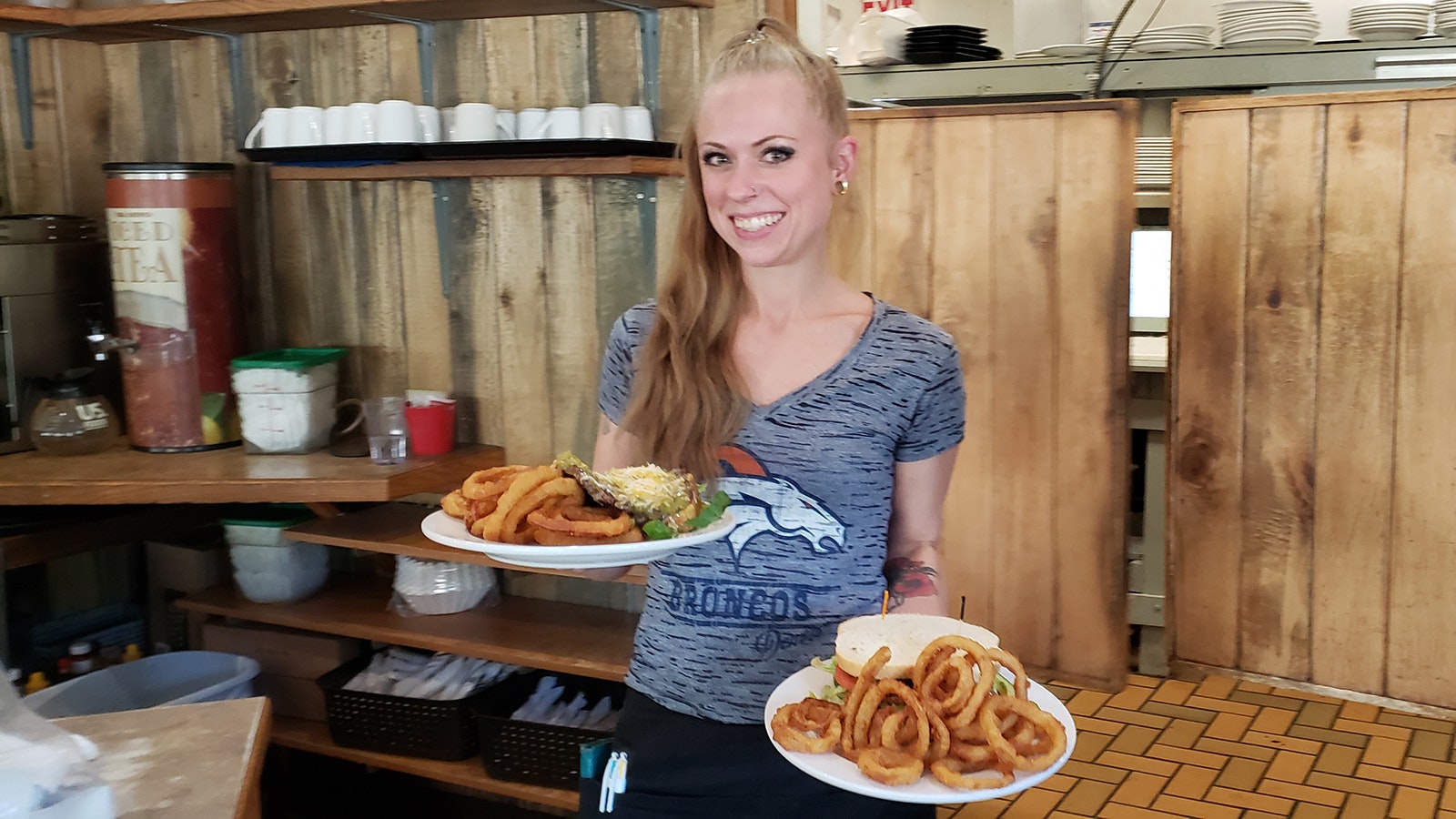 Kelsey Huntoon carries out plates heaped with onion rings and sandwiches during a lunch rush at J.W. Hugus Restaurant & Catering.