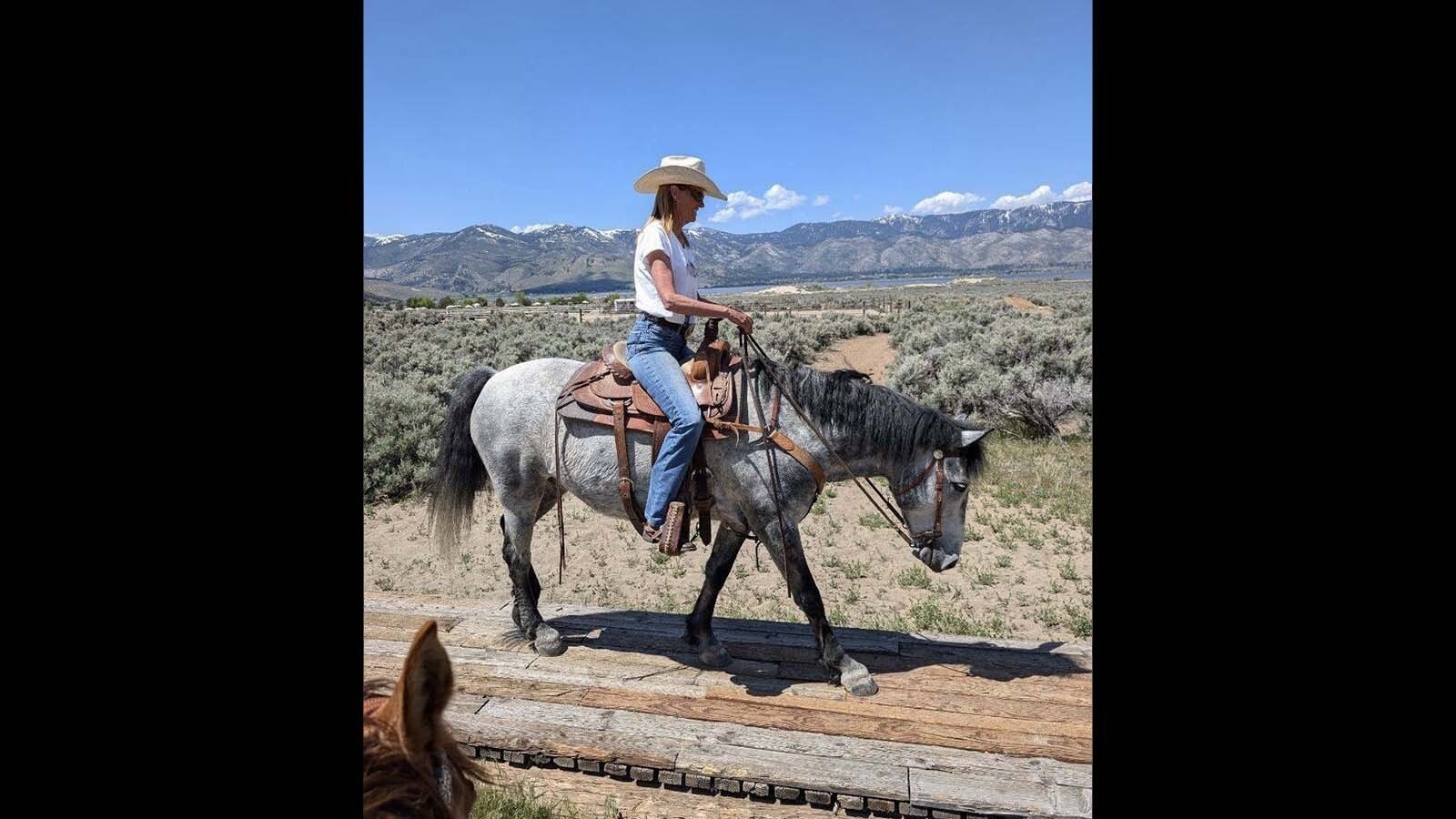 Jenny Lesieutre, president of Rangelands, Wildlife and Wild Horses LLC, rides a curly-haired mustang she adopted from a herd in Nevada.