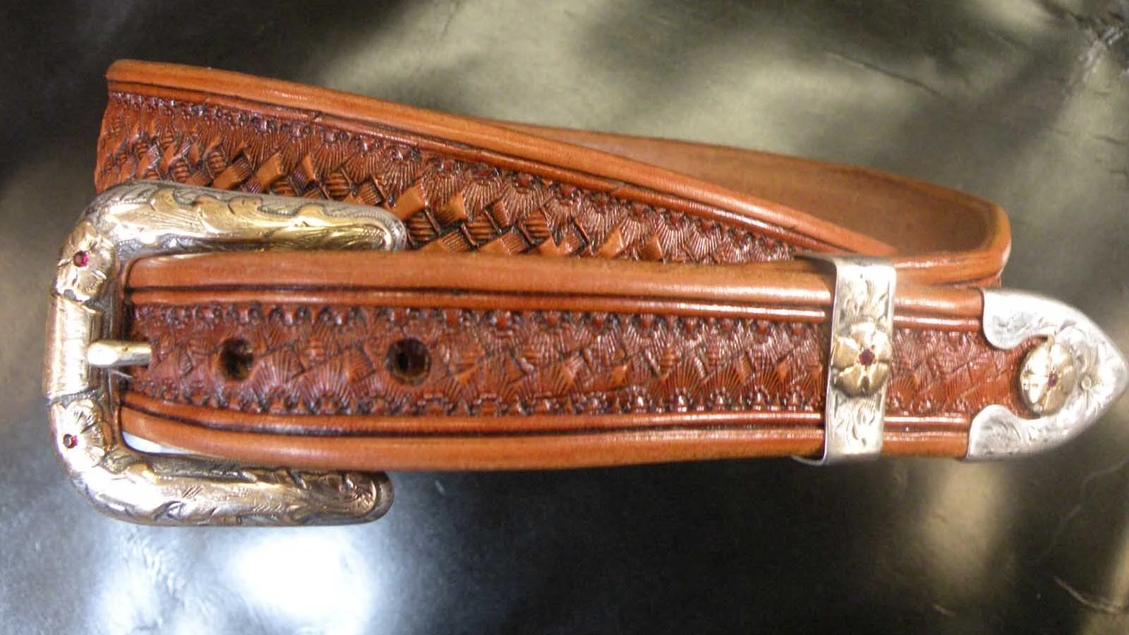 A belt with silver accents made by wyoming leatherworker and saddlemaker John L. Blair.