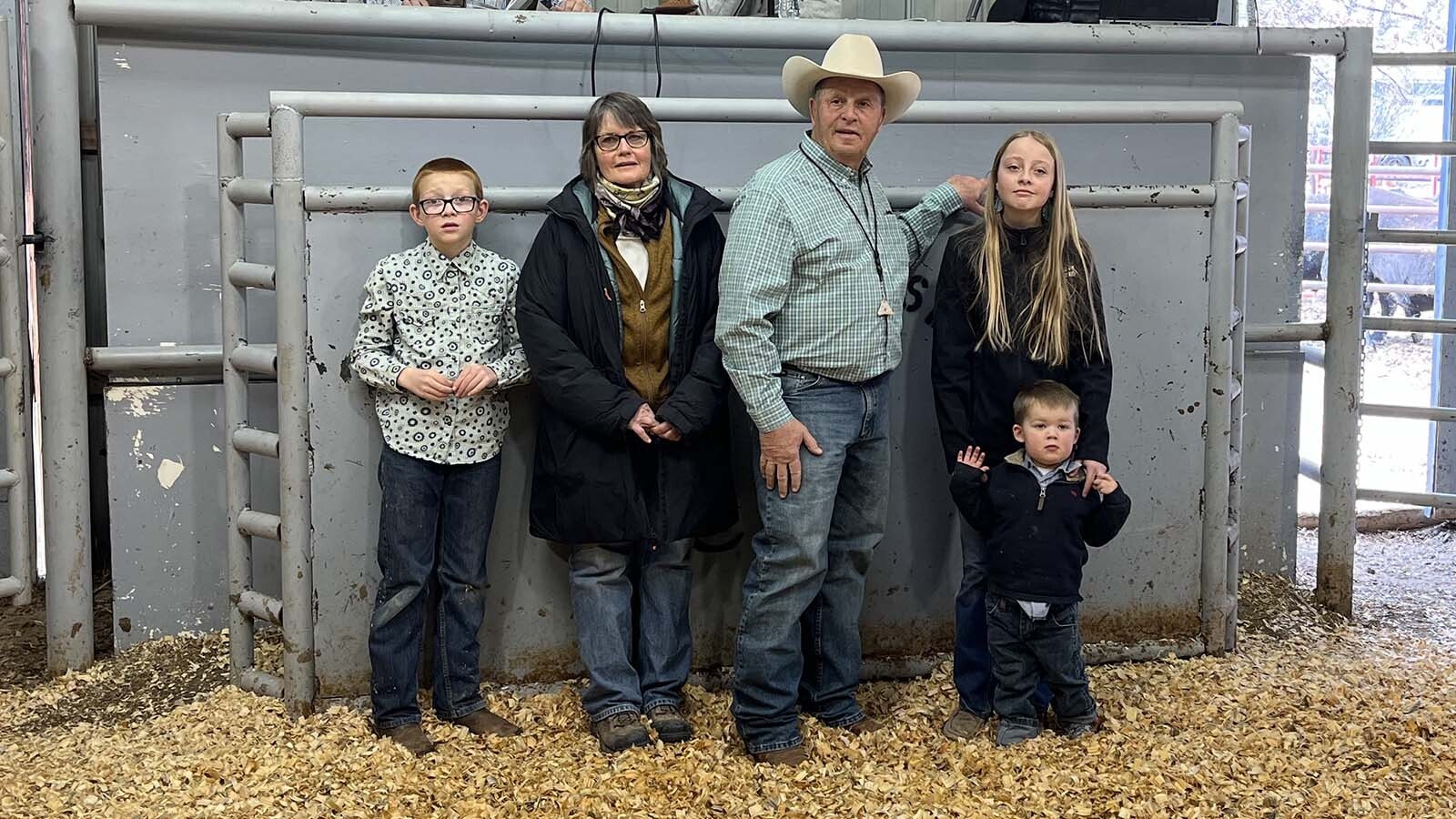 The Reyes family participates at the auction of some of their cattle. Jason Reyes is seated on left, and Jennifer Burr, the Reye’s daughter on the right beside auctioneer Lex Madden. Joni and Juan Reyes stand with three of their four grandchildren below.