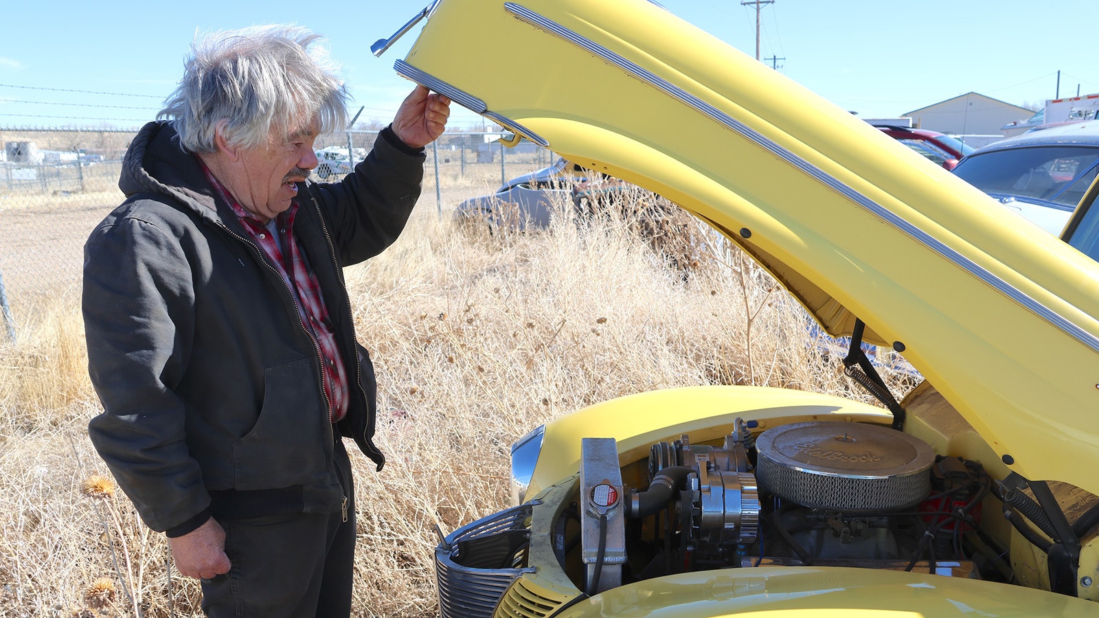 Gary Dickinson lifts the hood of his own restoration project on a 1940 Ford to show a 283 Chevy motor he installed in it.