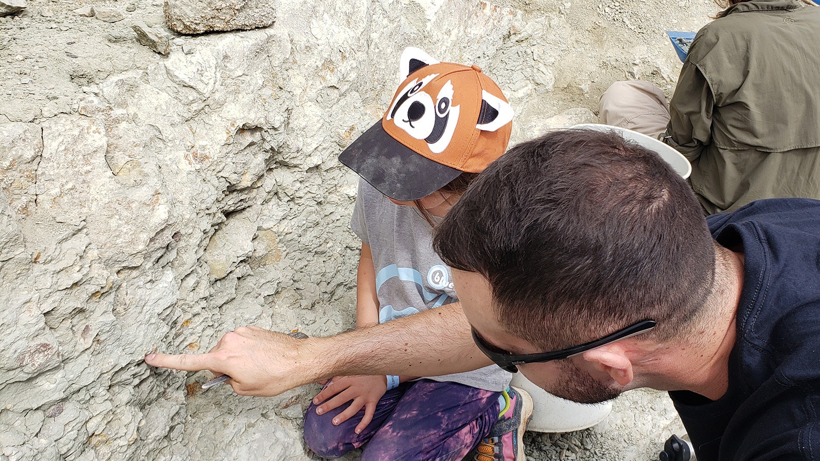 Dean Lomax stops to help 6-year-old Sierra, who wants to be a paleontologist someday, read the cliff wall to decide where to dig for a fossil.