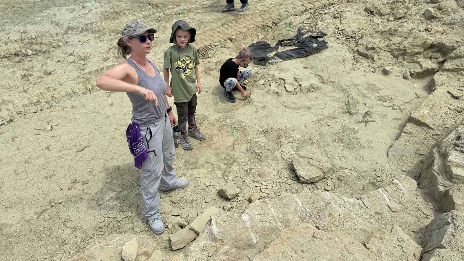 Fossil preparator Rachel Gray shows Nico Able, 11, and Thea Able, 9, the spot where the Children's Museum of Indianapolis excavated their exquisitely preserved Allosaurus specimen at the Jurassic Mile.