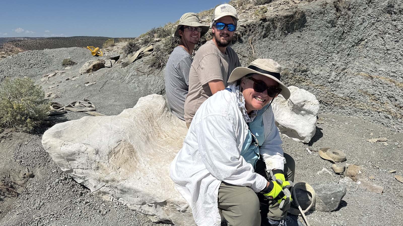 Melissa Connelly, a mitigating paleontologist and owner of Stratigraphic rex, LLC, takes a seat on the largest of the plaster jackets, containing the hips of a large Camarasaurus, in the pit where "Woody's Dinosaur" was excavated and removed in August 2025.