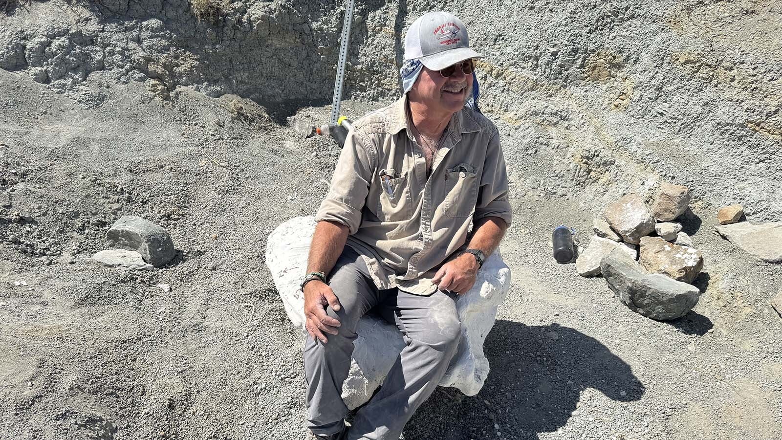 Brain Connelly rests his tail-end on a seat-shaped jacket containing several tail bones of a large long-necked dinosaur at the "Woody's Dinosaur" excavation near Alcova Reservoir.