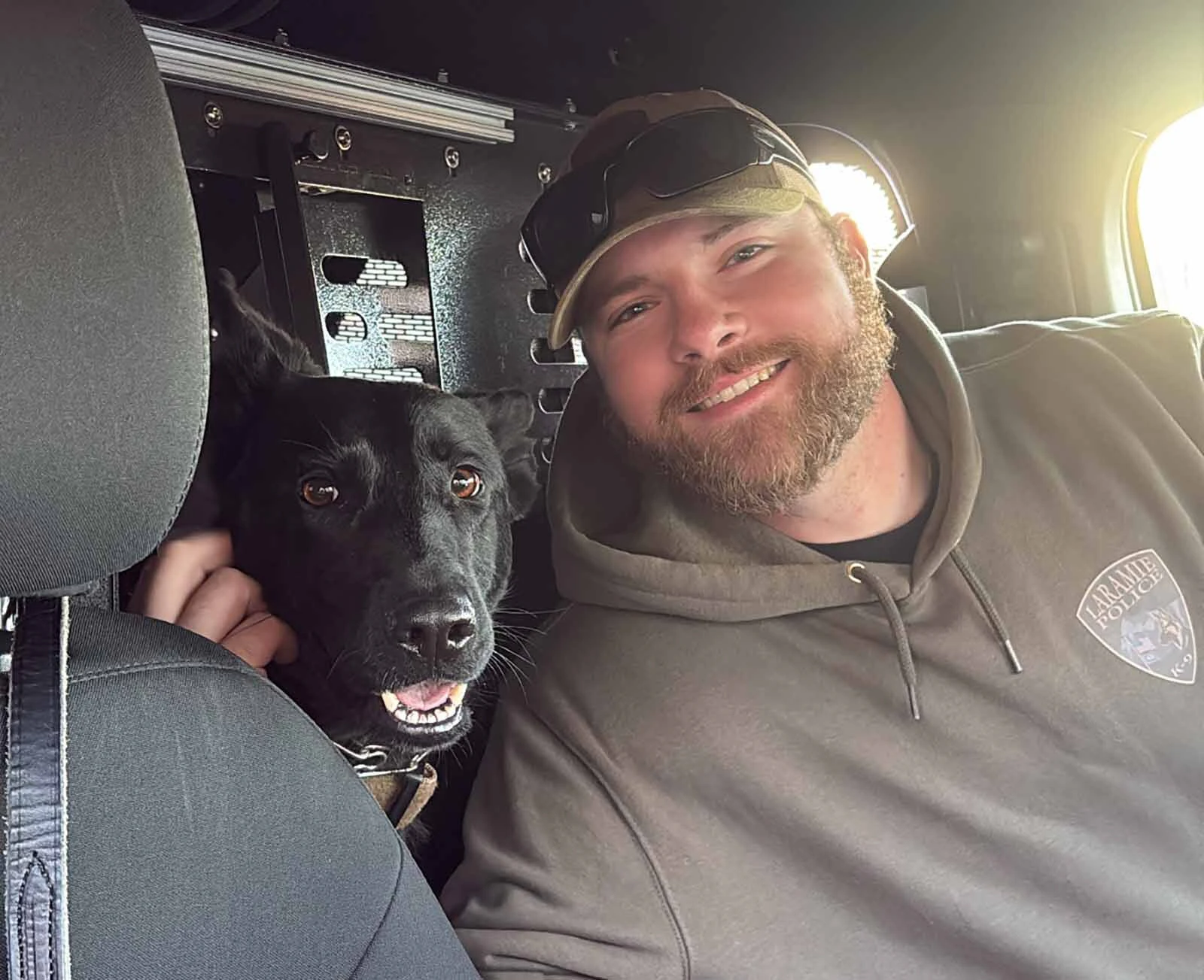 Laramie Police Officer Seth Meyer poses with K-9 Zara inside their patrol vehicle.