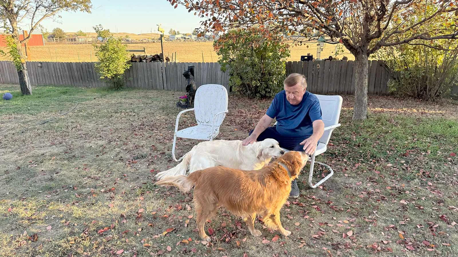 Keith Yosten plays with his two dogs in his backyard, which borders the open land behind his south Cheyenne home where a power transmission line is planned to connect to a Colorado wind farm project. He said he's lived there for 42 years and now fears the impacts the transmission line will have on the area.