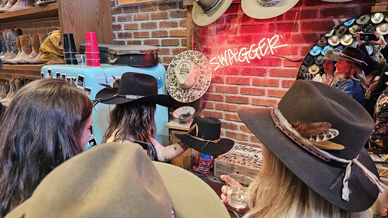 Mary Sullivan, Megan Prez and Anne Marie Cress watch while Sullivan's hat is branded. This is the final step, and the point of no return. Once the hat is branded, it is must be bought.