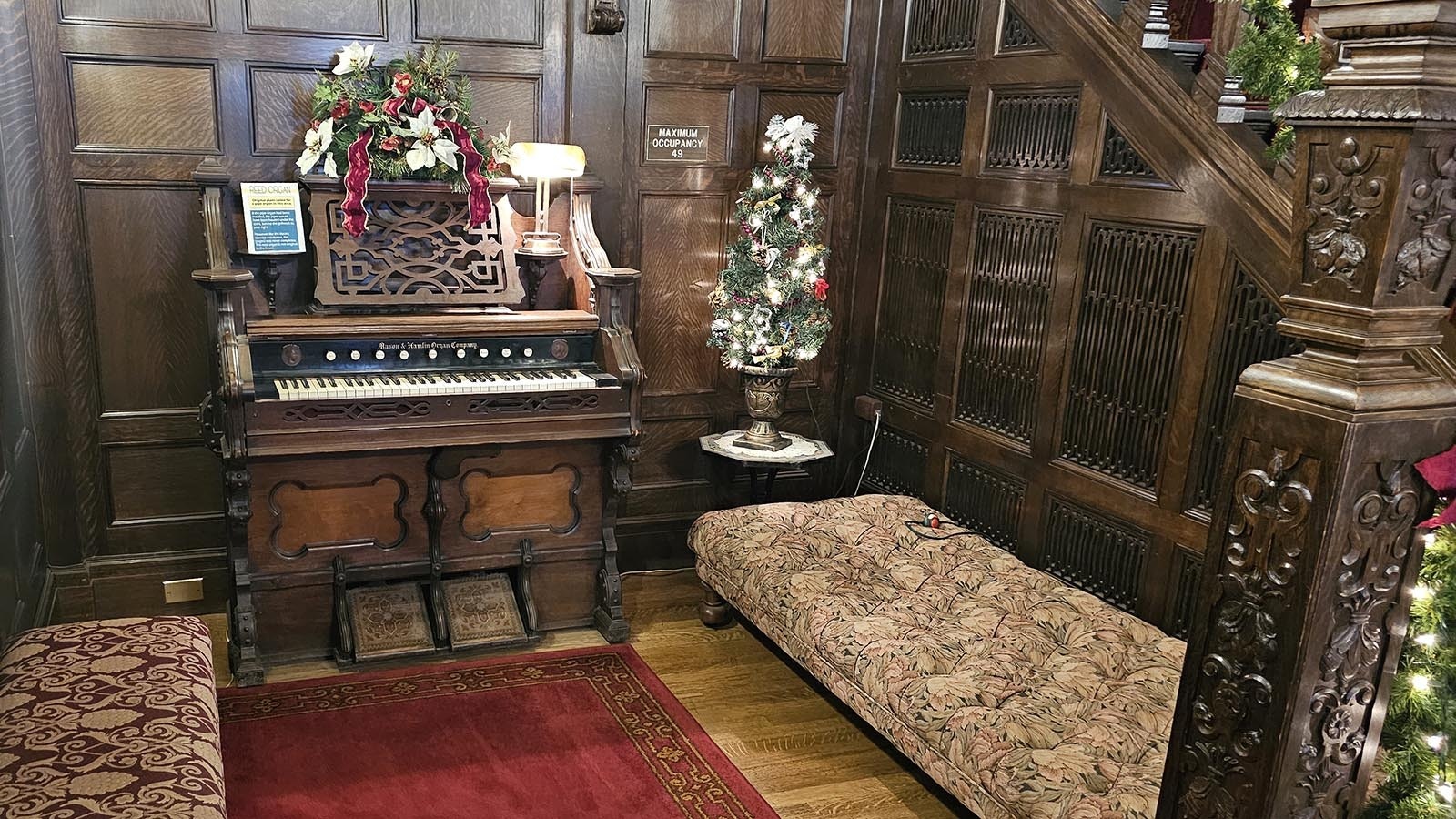 A miniature Christmas tree sits in the foyer of the Kendrick Mansion, alongside an organ and two benches.