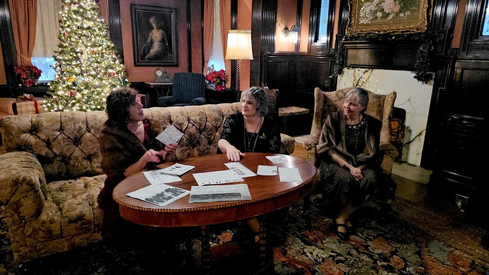 Eula Wulfjen Kendrick, played by Barbara Cavanagh, talks about newspaper clippings in her scrapbooks with her two guests, Matatie Wulfjen Williams (Michelle King) and Madge Eggleston (Kathy Pavatt).