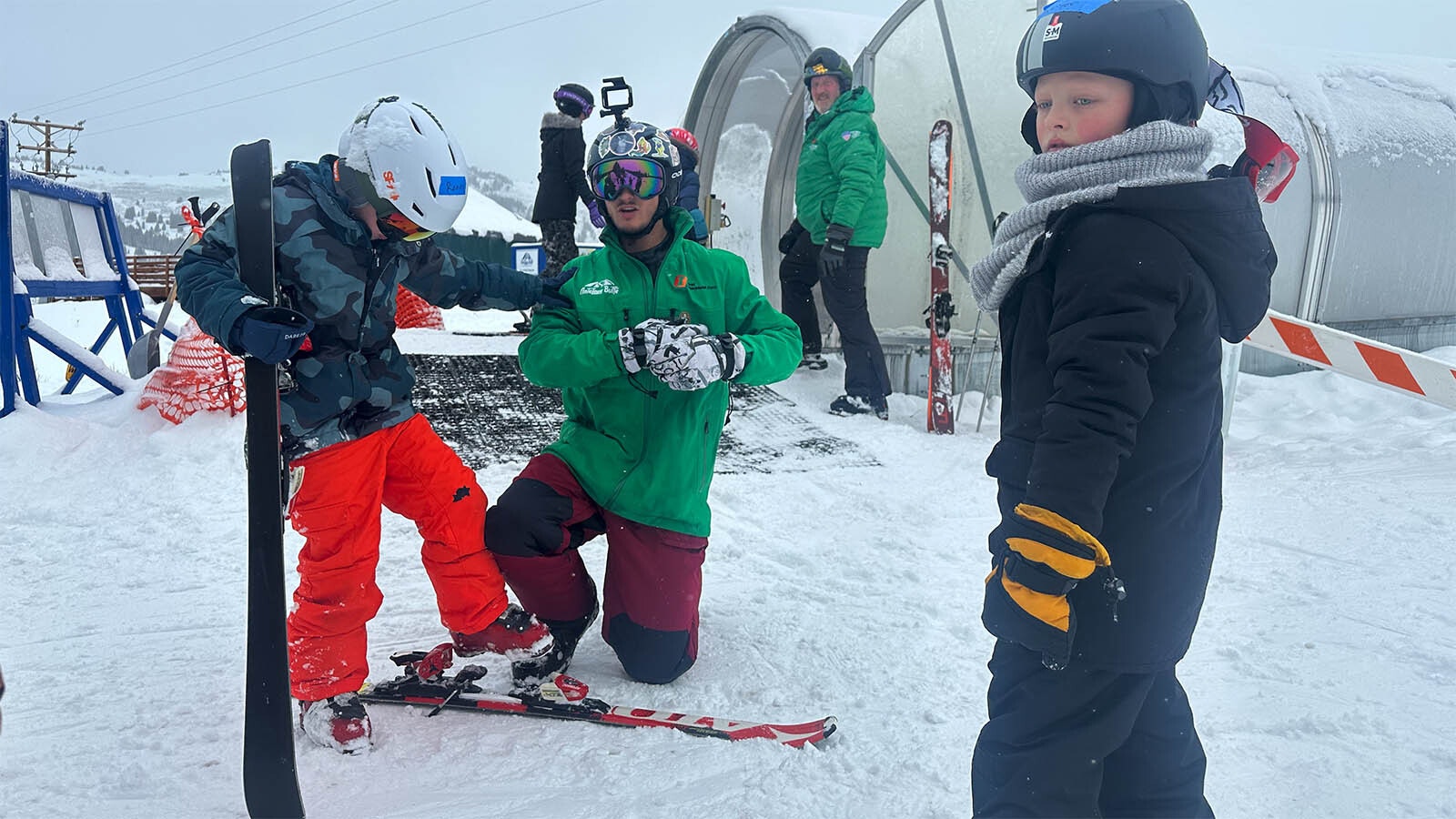 First Chair student Sawyer watches on as fellow student Ronin Wichern struggles to get into his skis. This is the first part of the lesson of learning to ski.