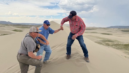 Shane and Pat White help Bill Sniffin get to the summit of one of the tall sand dunes.