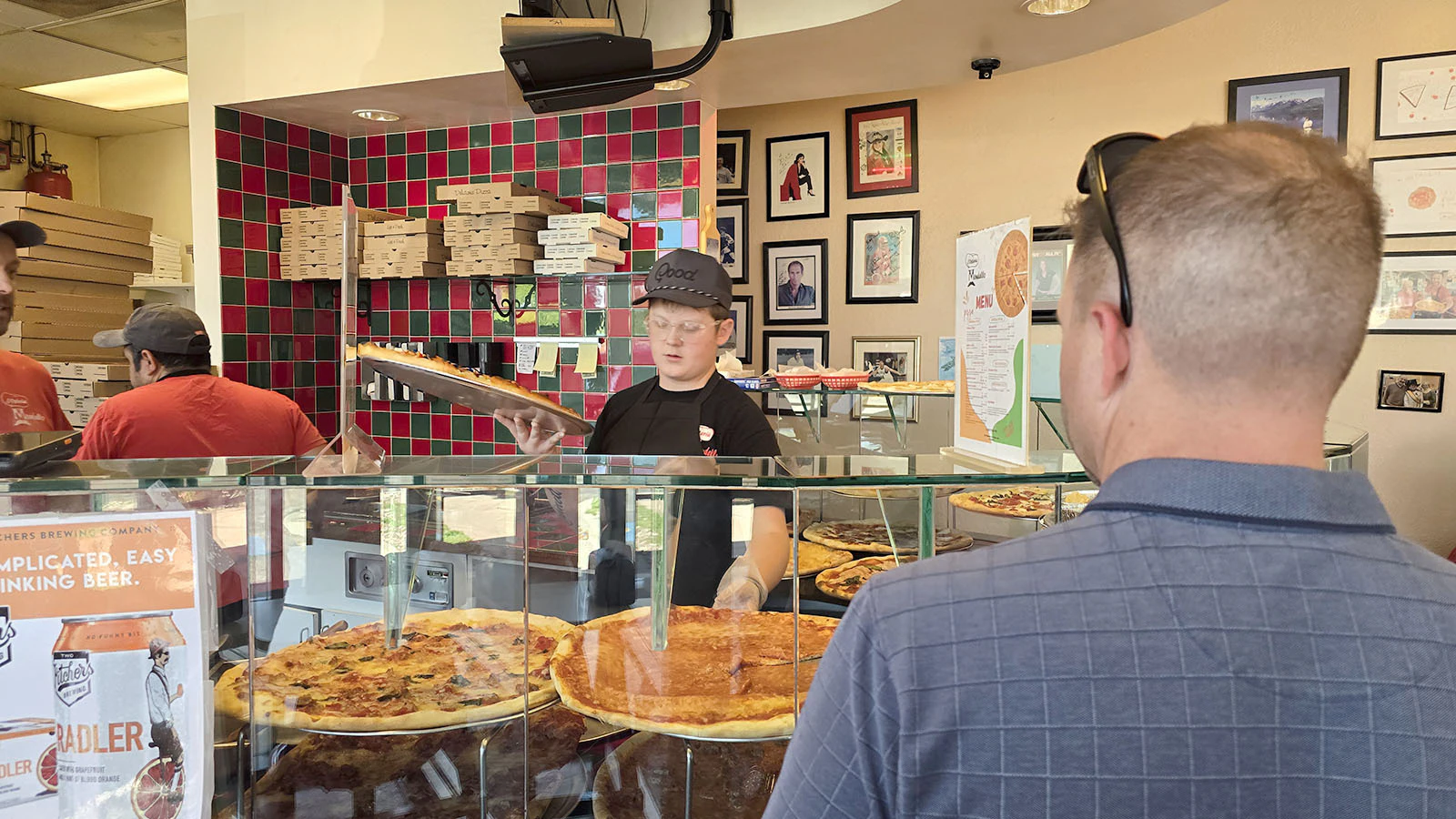 Bryce Robinett works on preparing a pizza order while a customer looks on at L'Osteria Mondello in Cheyenne. Robinett is part of a small army of teenagers working at the pizzeria, which has a waiting list of 17 youths who want to work there.