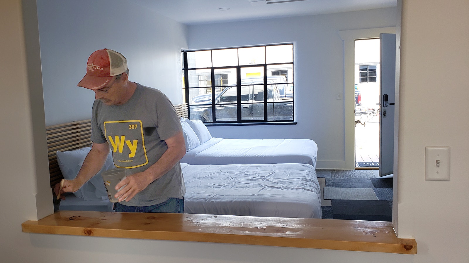Steve McKinney adds a coat of varnish to a shelf built into the window-sized cutout in one of the larger rooms that includes a kitchenette.