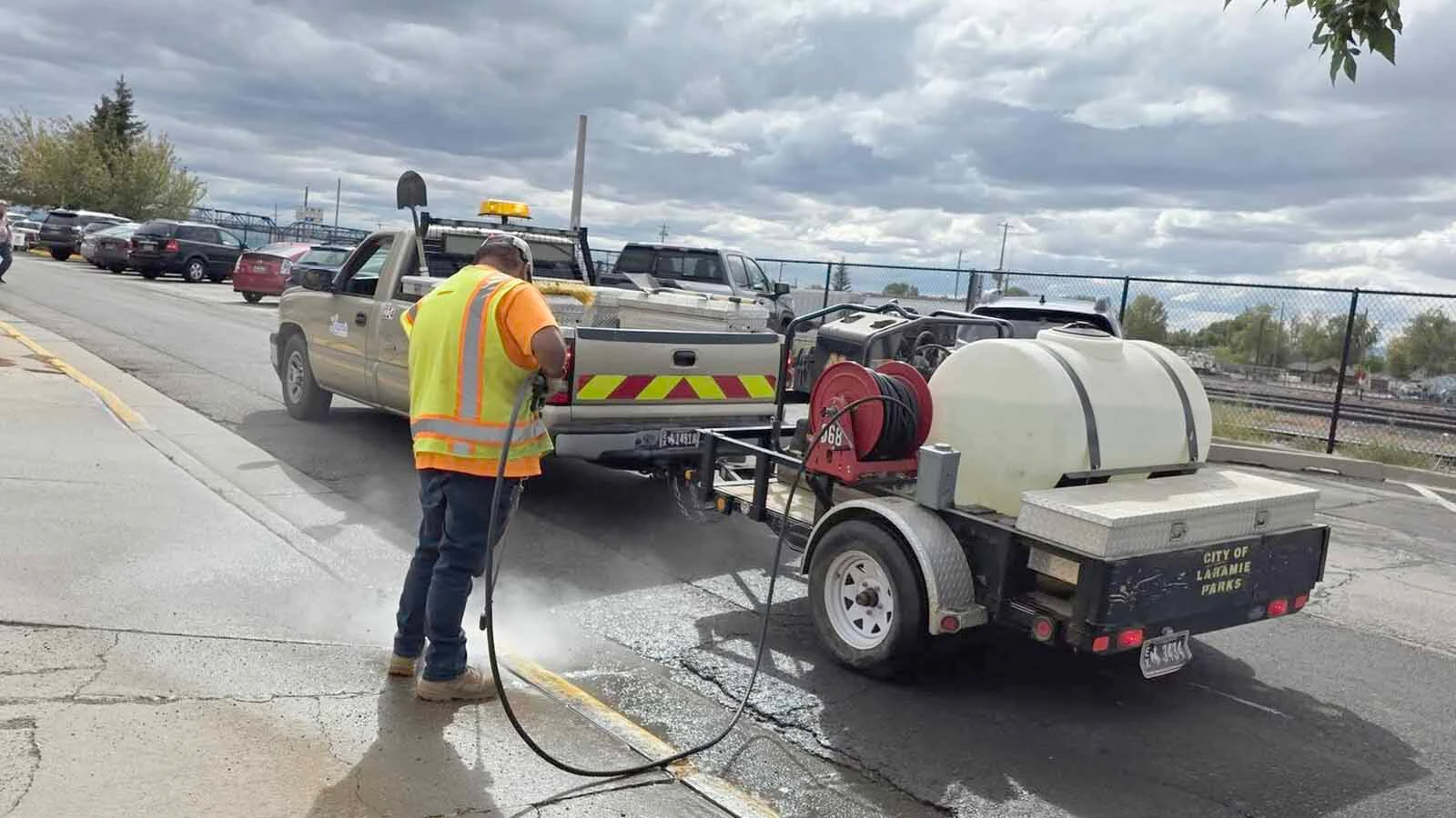 A Laramie city road worker uses a pressure washer to fix an epically bad curb painting job, which then also created a horrible-looking fix trying to cover the yellow overspray with gray paint.