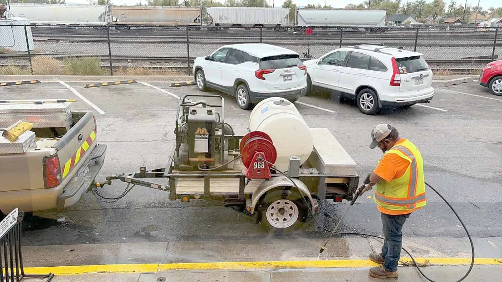 A Laramie city road worker uses a pressure washer to fix an epically bad curb painting job, which then also created a horrible-looking fix trying to cover the yellow overspray with gray paint.