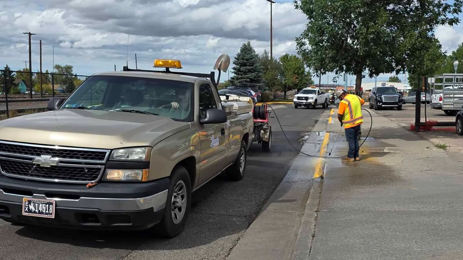 A Laramie city road worker uses a pressure washer to fix an epically bad curb painting job, which then also created a horrible-looking fix trying to cover the yellow overspray with gray paint.