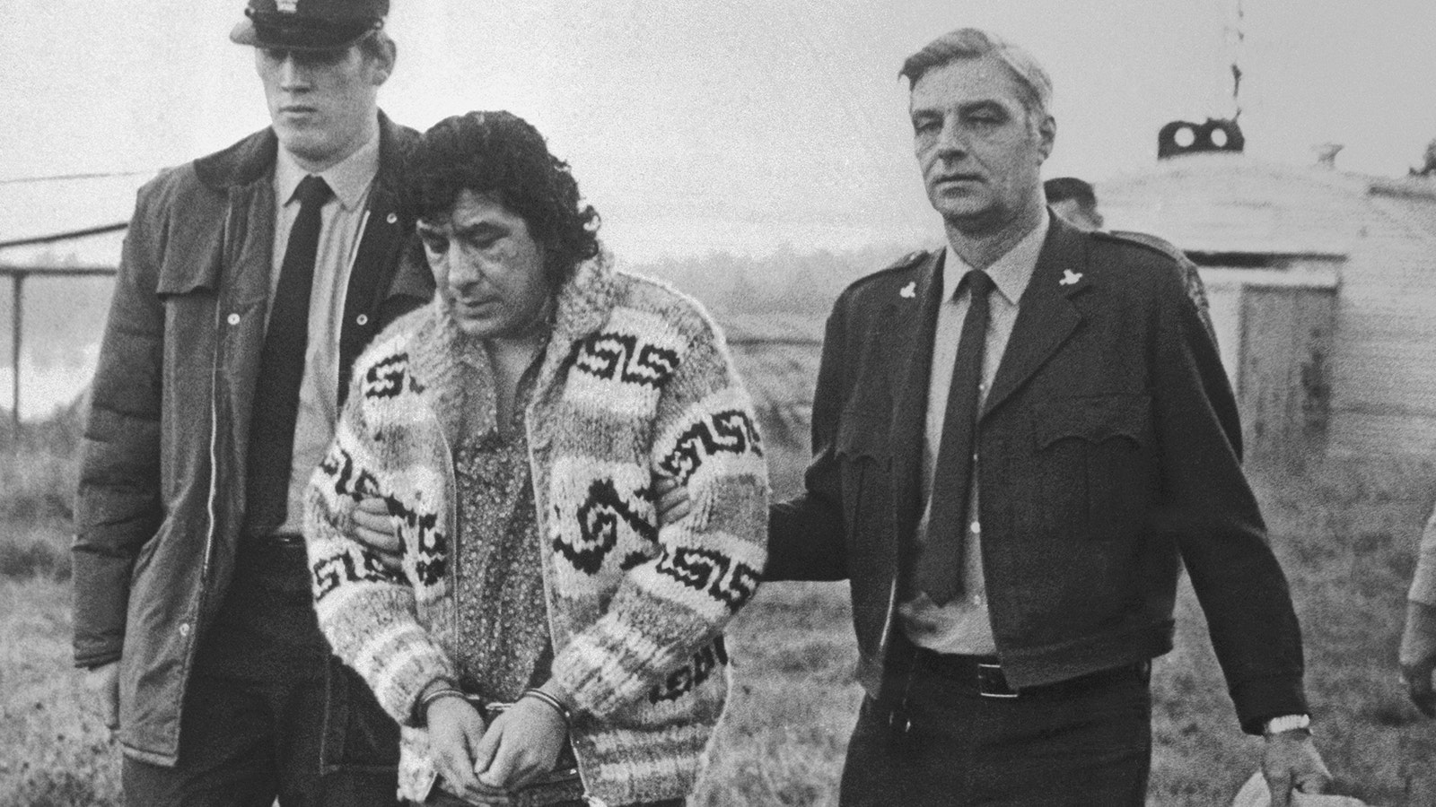 Leonard Peltier, American Indian Movement leader, is led across Okalla prison exercise yard to a waiting helicopter. After a prolonged legal battle, Peltier was ordered deported by Canadian Justice Minister Ron Basford to face charges of murdering two FBI agents.