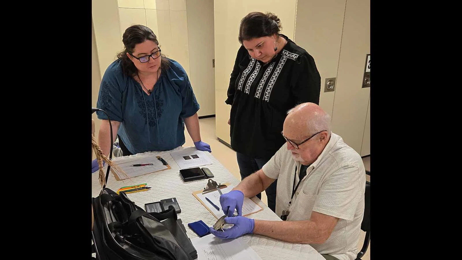Lawrence Lee, seated, examines rare Lewis and Clark peace medals owned by the Buffalo Bill Center of the West's Indian Plains Museum.