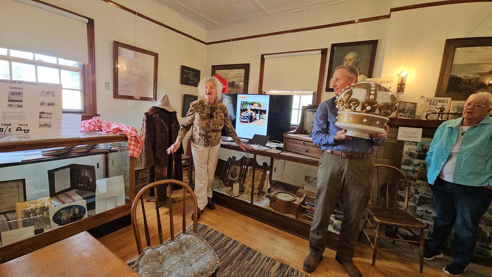 Nancy Anderson, left, talks about her idea to restore a gas station that used to be along the Lincoln Highway at the Hanna Museum, while a friend holds up an old Standard Oil Crown from the old Coyote Springs gas station, during  the Alliance for Historic Wyoming's Lincoln Highway "Unbarred" tour.