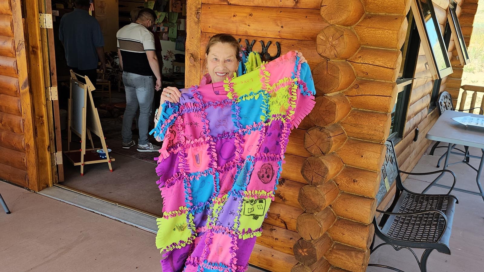 Cheryl Gowdy holds up a kindness quilt. Each block has artwork and a kindness wish from a child who visited Little House. The heartwarming quilts will be given to homeless pets, and soon, homeless people as well.