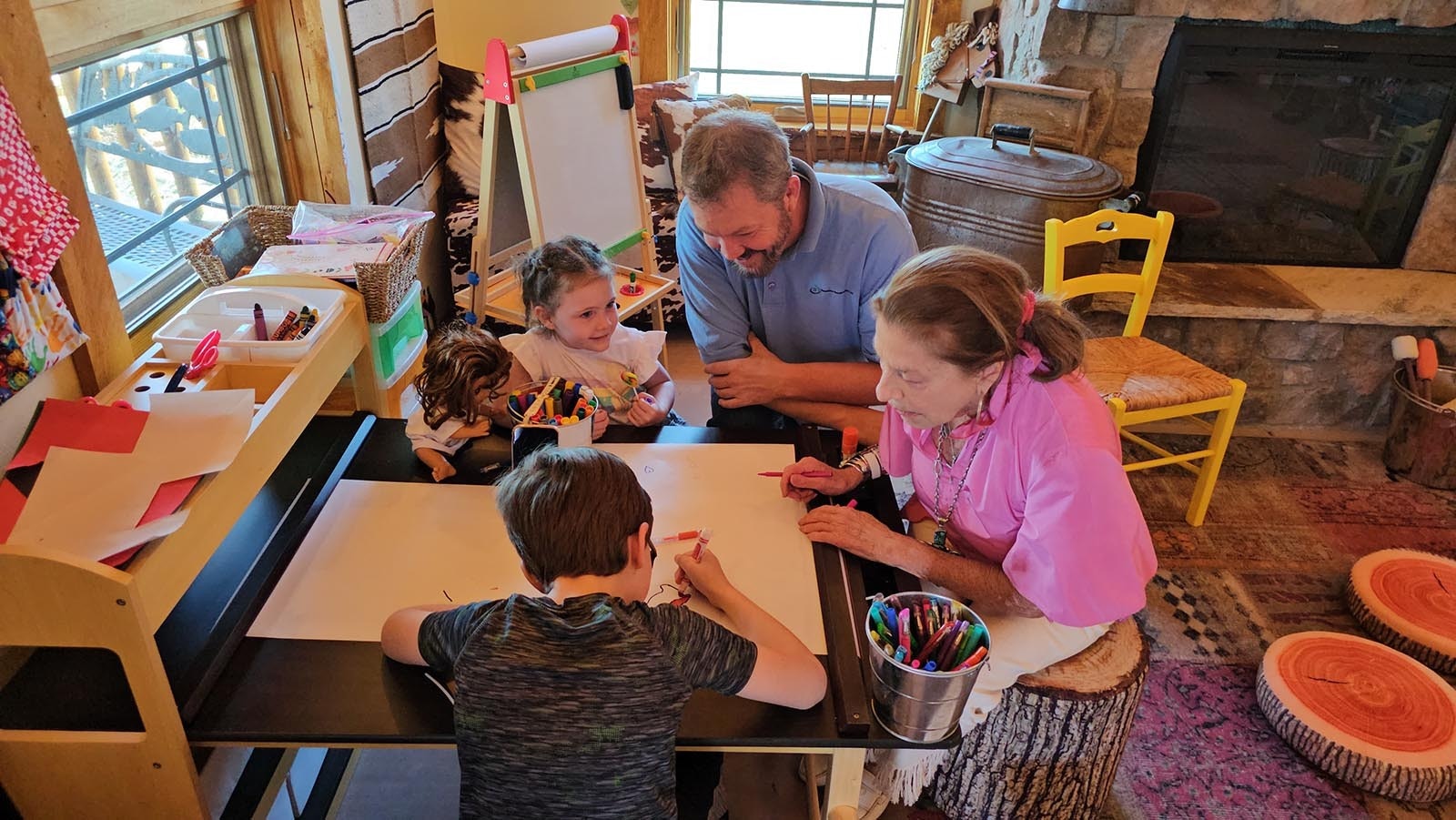 Cheryl Gowdy draws with some of the children visiting Little House while architect Richard Dixon looks on.