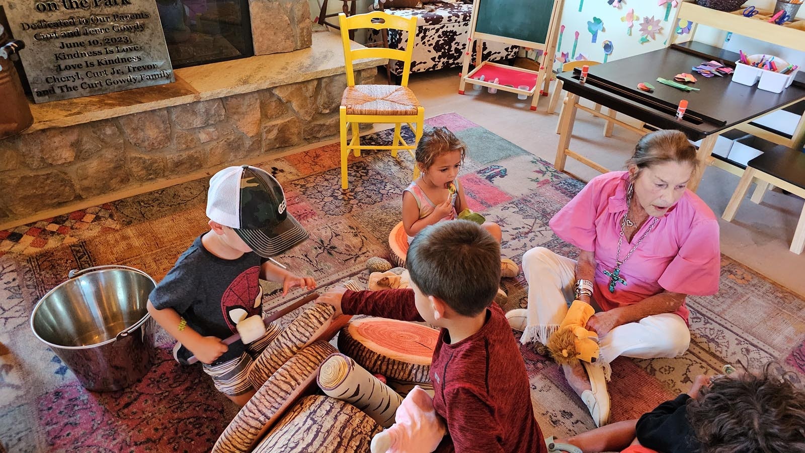 Cheryl Gowdy watches as children build a pretend log fire in Little House.