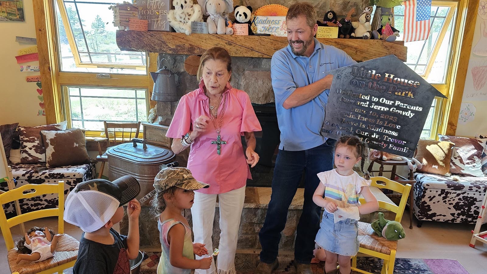 Cheryl Gowdy talking to children at Little House while Richard Dixon, Little House's architect, holds up a plaque made for Little House.