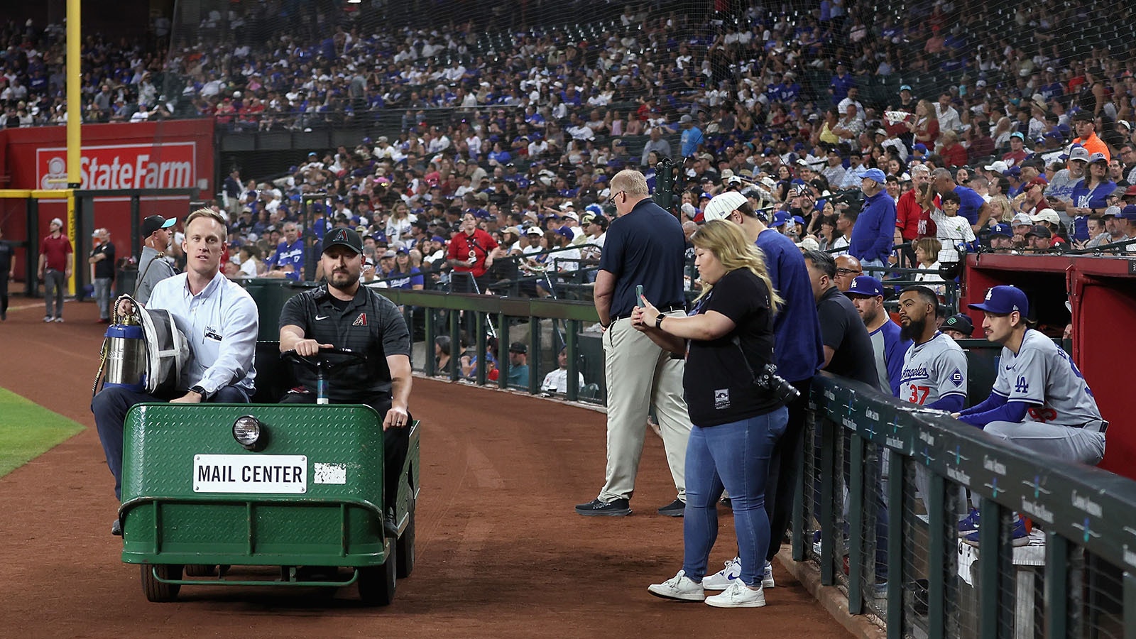 Beekeeper Matt Hilton, left, arrives to Chase Field to remove a colony of bees that formed on the net behind home plate during a delay to the MLB game between the Los Angeles Dodgers and the Arizona Diamondbacks on April 30, 2024, in Phoenix, Arizona.